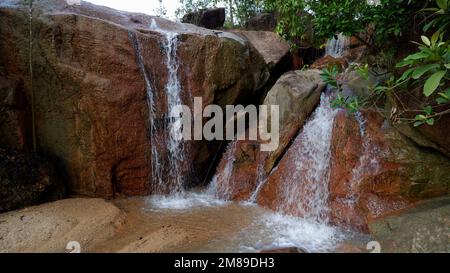 Two Small Waterfalls Flowing From Large Natural Rocks Stock Photo
