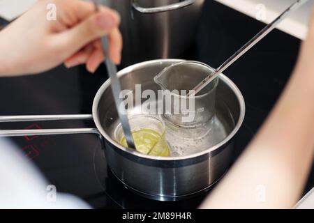 Heat beakers of water and jojoba oil in boiling water, record the temperature with a thermometer Stock Photo