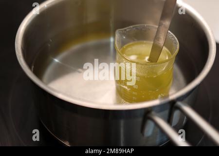 Heat beaker of jojoba oil in boiling water, record the temperature with a thermometer Stock Photo