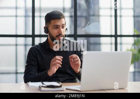 Young handsome male customer support phone operator with headset working in his office. Stock Photo