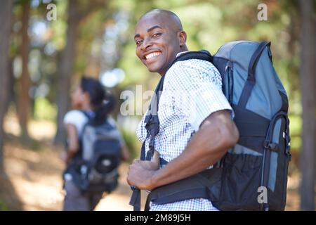 I like to let her lead sometimes...Portrait of a young couple wearing backpacks while enjoying a hike in the woods. Stock Photo