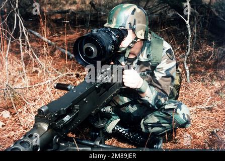 A soldier aims an M-2 .50-caliber machine gun equipped with an AN/TVS-5 crew-served weapon sight. Country: Unknown Stock Photo