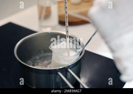 Heat beaker of water and jojoba oil in boiling water, record the temperature with a thermometer Stock Photo