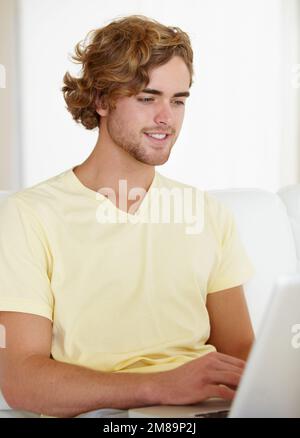 Fast internet is always a plus. A handsome young man browsing the internet from the comfort of his couch. Stock Photo
