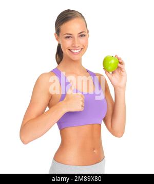 Thumbs up, apple and fitness of woman in studio isolated on white background. Face, portrait and female model with hand gesture and fruit for healthy Stock Photo