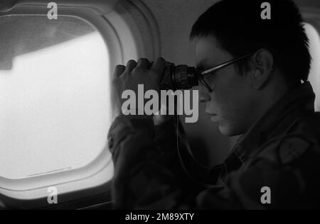 A U.S. military rescue team member uses binoculars to search for seven walrus hunters missing since June 2nd. Searchers received permission to fly three Alaska Army National Guard UV-18 Twin Otter aircraft in restricted airspace after the hunters, from St. Country: Unknown Stock Photo