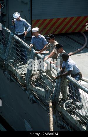 Crew members aboard the salvage ship USS PRESERVER (ARS-8) haul a piece ...