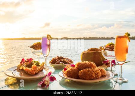 Thai cuisine set, grilled river prawn, catfish curry, curry steamed seafood in a coconut cup, and deep-fried shrimp cake served with wine and oysters. Stock Photo