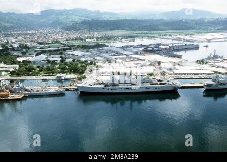A port view of the British light aircraft carrier HMS ARK ROYAL (R-07) moored to a pier. The stern of the battleship USS NEW JERSEY (BB-62) is on the left. SUBSTANDARD IMAGE. Base: Naval Station, Subic Bay State: Luzon Country: Philippines (PHL) Stock Photo