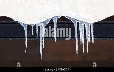Icicles hang on a house roof, close up photo with selective soft focus Stock Photo