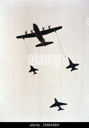 A KC-130 Hercules aircraft refuels an AV-8B Harrier aircraft, left, an F/A-18 Hornet aircraft, right, as an EA-6B Prowler aircraft brings up the rear of the formation during Airshow '88. Base: Marine Corps Base, Quantico State: Virginia (VA) Country: United States Of America (USA) Stock Photo