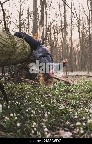 Laughing woman hanging on fallen tree scenic photography Stock Photo