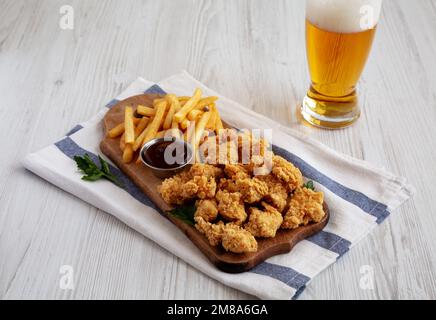 Homemade Popcorn Chicken with BBQ Sauce on a Rustic Wooden Board, side view. Stock Photo