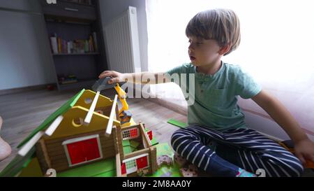 Child playing in room with mother building traditional wooden home toy. Little boy builds house with parent 2 Stock Photo