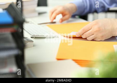 Closeup of man hands opening yellow padded envelope with letter at table Stock Photo