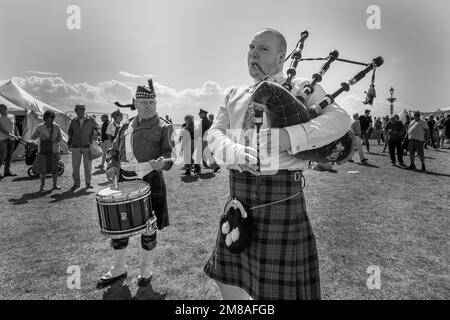 A man plays the bagpipes while another plays the drums during a 1940s wartime weekend in Lytham, Lancashire, in 2022. Stock Photo