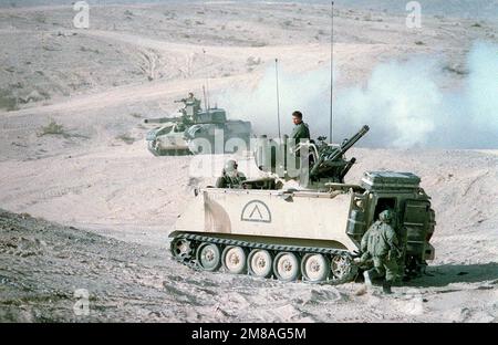 A soldier of the 24th Infantry Division (mechanized) moves toward the open rear hatch of an M-163 Vulcan self-propelled anti-aircraft gun, which consists of an M-168 20mm Vulcan cannon with radar fire control mounted on a modified M-113 armored personnel carrier. In the background is a National Training Center opposing forces (OpFor) M-551 Sheridan light tank modified to resemble a Soviet T-72 main battle tank. Base: Fort Irwin State: California (CA) Country: United States Of America (USA) Stock Photo