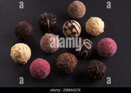 photo a lot of chocolates in icing lying next to each other on a black background Stock Photo