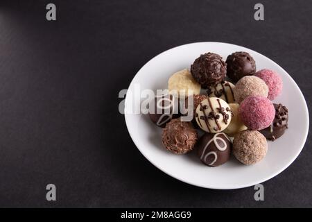 A photo of many different chocolates lying in a white round plate Stock Photo
