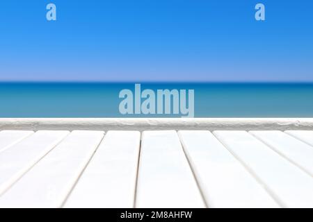 White plank wooden surface against defocused blue sea background. Stock Photo