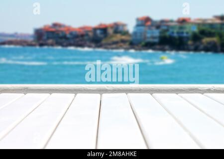 Plank wooden surface against defocused blue sea background with seaside resort Stock Photo