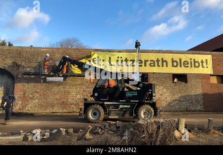 Erkelenz, Germany. 13th Jan, 2023. Workers remove a banner 'Lützerath bleibt!' from a wall. The energy company RWE wants to excavate the coal lying under Lützerath - for this purpose, the hamlet on the territory of the city of Erkelenz at the opencast lignite mine Garzweiler II is to be demolished. Credit: Petra Albers/dpa/Alamy Live News Stock Photo