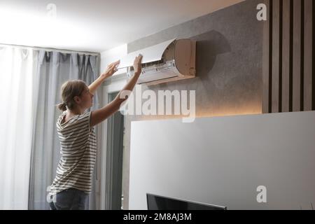Woman repairing air conditioner at home. Stock Photo