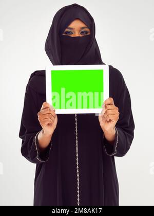 Muslim woman, tablet and green screen for marketing, advertising or mockup against a grey studio background. Portrait of woman in hijab holding Stock Photo