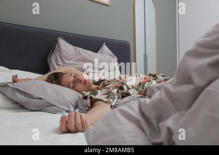 Young brunette between crumpled sheets in a king size bed Stock Photo