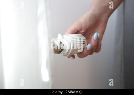 Woman's hand adjusting radiator thermostat valve, controlling central heating system Stock Photo