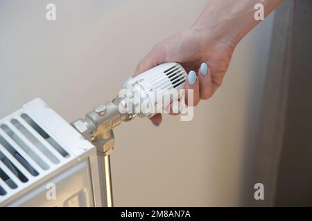 Woman's hand adjusting radiator thermostat valve, controlling central heating system Stock Photo