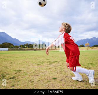 He spends hours on the training ground. Full length shot of a young boy playing with a soccer ball. Stock Photo