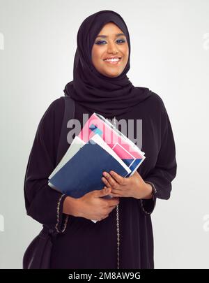 Portrait, muslim and books with a student woman in studio on a gray background for learning or education. Islam, university and study with an islamic Stock Photo