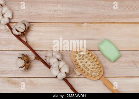 massage brush and soap bar on light wooden table, cotton flower closeup. sponge Stock Photo