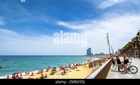 Barcelona, Spain - July 6, 2017:  day view of tourists walking by Passeig Maritim in front of Barceloneta beach and Mediterranean, sea with W hotel in Stock Photo