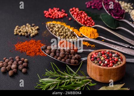 Several types of spices in metal spoons paprika, tomatoes, curry, beets, cumin, turmeric, fennel, spirulina, allspice of different colors on a black c Stock Photo