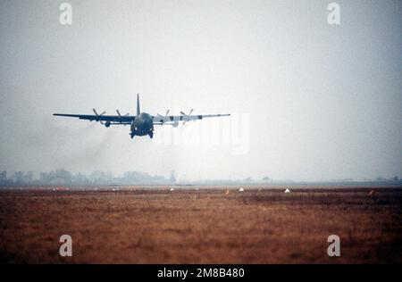 A 37th Tactical Airlift Squadron C-130E Hercules aircraft makes a grass  strip landing at Drop Zone Juliet near Aviano Air Base during an evening  training mission. Country: Italy (ITA Stock Photo 