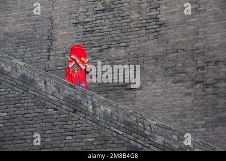 Xian, China - October 29, 2011: a Chinese bride in traditional costumes walking down an ancient city wall Stock Photo