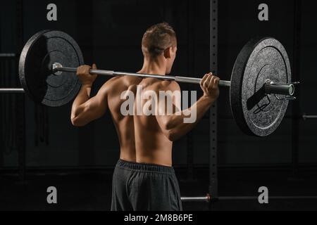 Man doing back squats exercise with a barbell. Crossfit training in a gym. Stock Photo