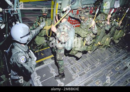 TSGT D.K. Kottwick, loadmaster, 37th Tactical Airlift Squadron, helps members of Co. C, 3rd Bn., 325th Inf., Airborne Combat Team out the door as they drop from their C-130E Hercules aircraft. The squadron is supporting an Army training and evaluation program (ARTEP) mission. Country: Deutschland / Germany (DEU) Stock Photo