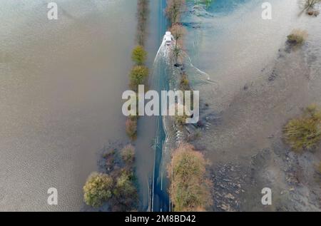 Heuchelheim, Germany. 13th Jan, 2023. A truck drives over a flooded country road near Heuchelheim in Hesse (aerial photo taken with a drone). With further precipitation, more rivers and streams could burst their banks. Credit: Boris Roessler/dpa/Alamy Live News Stock Photo