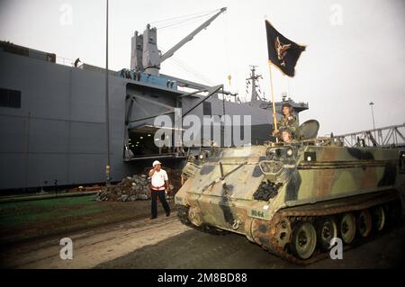SPECIALIST Willie Black holds the battalion flag as the first M113 armored personnel carriers to the 1ST Battalion, 61st Infantry, 5th Infantry Division (Mechanized), is unloaded from the cargo ship USNS BELLATRIX (T-AKR 288) at the Miraflores Locks. State: Canal Zone Country: Panama (PAN) Stock Photo