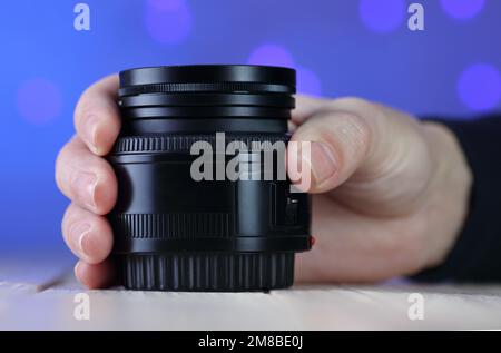50mm lens in hand on table and colored background Stock Photo