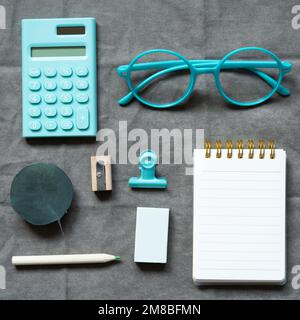 Mint calculator, eyeglasses, notebook and office supply on gray fabric background. flat lay, top view Stock Photo