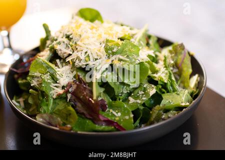 Fresh green salad topped with grated parmesan cheese and grated lemon zest Stock Photo