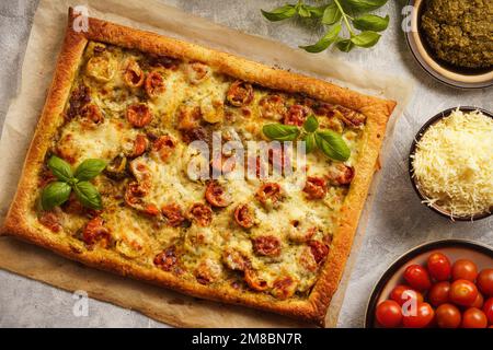 Homemade puff pastry pie with pesto, tomatoes and mozzarella like pizza caprese. Stock Photo