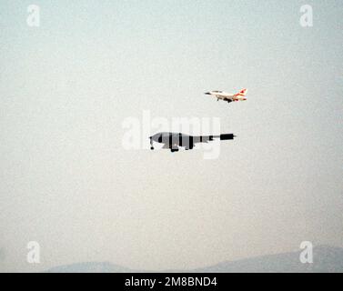 An F-16B Fighting Falcon chase plane accompanies a B-2 advanced technology bomber aircraft on its first flight, at the Air Force Flight Test Center. Base: Edwards Air Force Base State: California (CA) Country: United States Of America (USA) Stock Photo