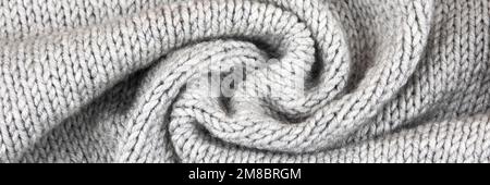 Knitted gray background. Close-up of a knitted blanket. Wavy folds material. Knitted warm grey sweater or scarf. Banner, copy space Stock Photo