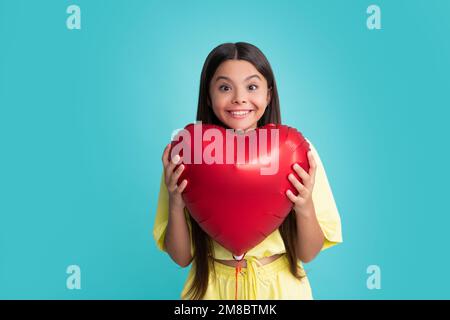 Happy girl face, positive and smiling emotions. Portrait of child teenage girl with heart balloon. Valentines day concept. Excited face, cheerful Stock Photo