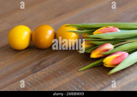 Golden Easter eggs with tulips on a wooden background Stock Photo